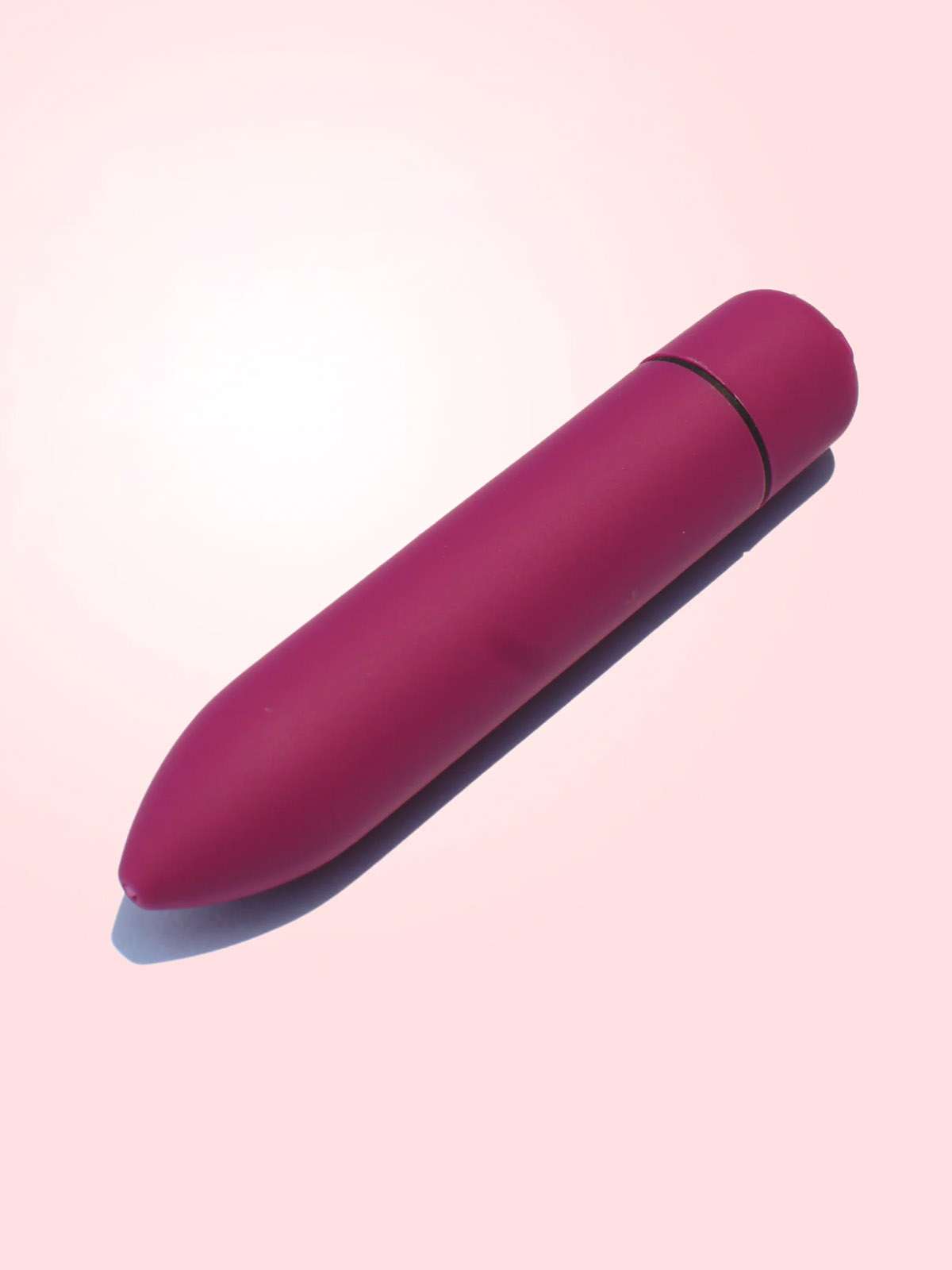 Lovenjoy premium purple clitoral vibrator with 10 modes and pinpoint stimulation tip, made of medical-grade silicone on a pink background.