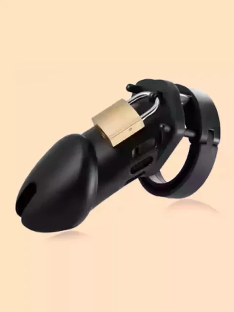 An ergonomic curved black male chastity cage with a hinged base ring, secured by a small brass padlock, isolated against a light peach background.